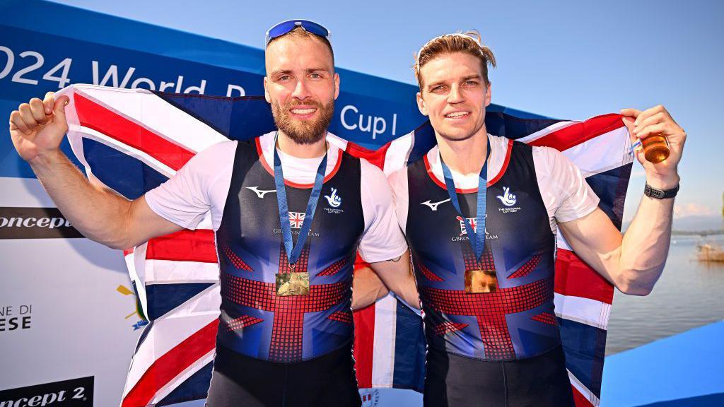 Ollie Wynne-Griffith and Tom George (right) hold a flag behind them after victory in the World Rowing Cup