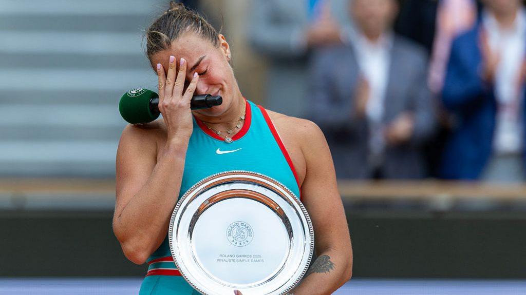 Aryna Sabalenka in tears after the French Open final as she holds the runner-up plate trophy