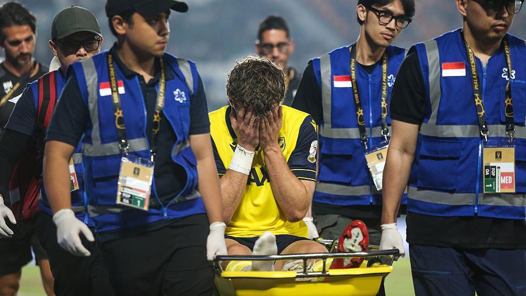 Ole Romeny being stretchered off the field of play with his head in his hands
