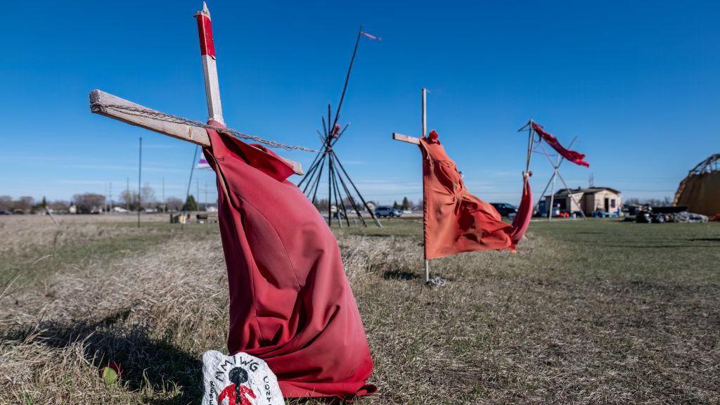 Red dresses on crosses are displayed at the entrance of a makeshift camp near near the Prairie Green landfill in Winnipeg, Manitoba