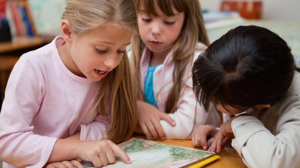 Three primary school pupils looking at the same book on a table.