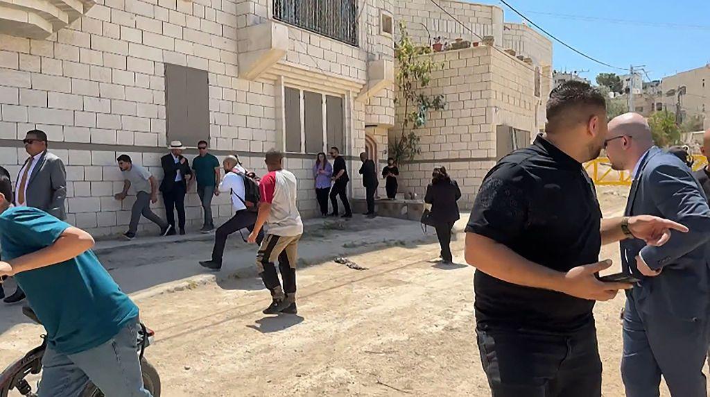 Members of a diplomatic delegation reacting after shots were fired as they gathered at an entrance Jenin camp, some apopear to be running away and others looking behind them 