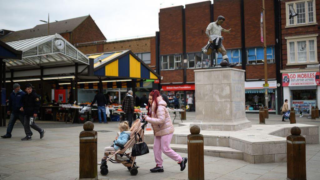 Members of the public walk through the town centre in Dudley in central England on April 29, 2022