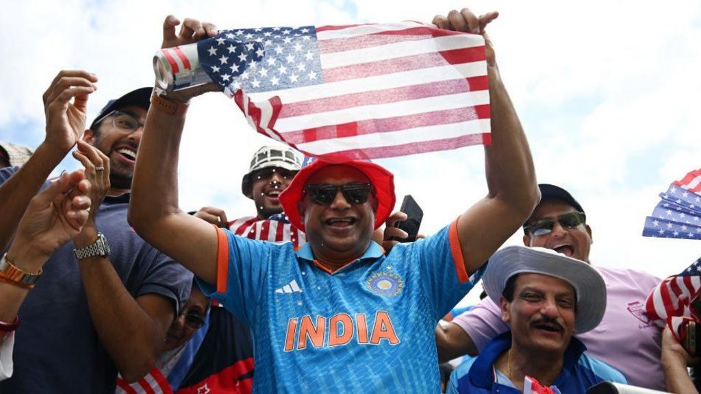 A fan wearing an India shirt holds up a USA flag