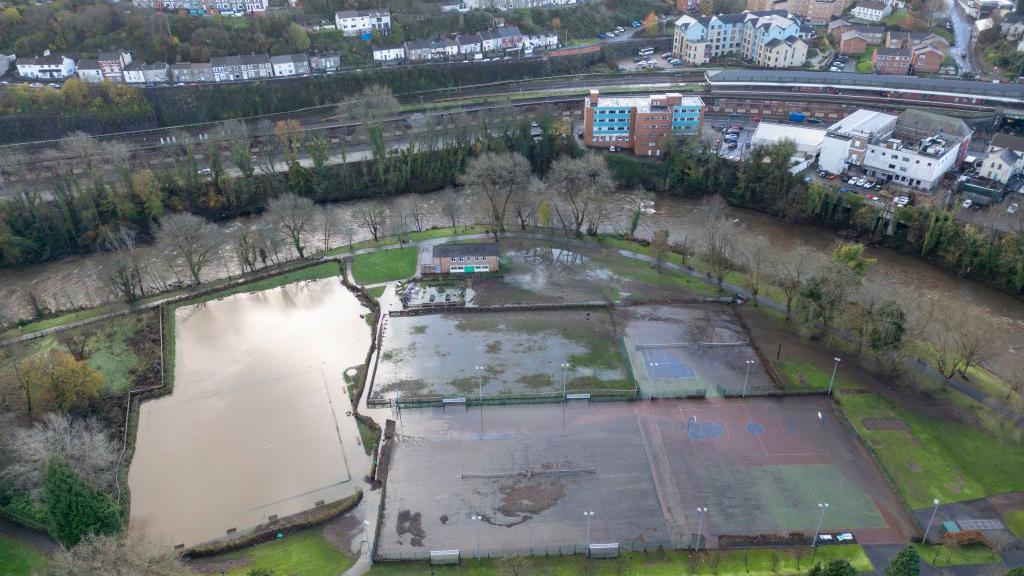 An aerial view of sports courts in Ynysangharad Park which flooded after the River Taff breached its banks. the fields are covered in water 