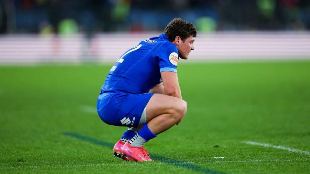 Dejected Italy player Alessandro Garbisi squats on his haunches during the thumping home defeat by Italy