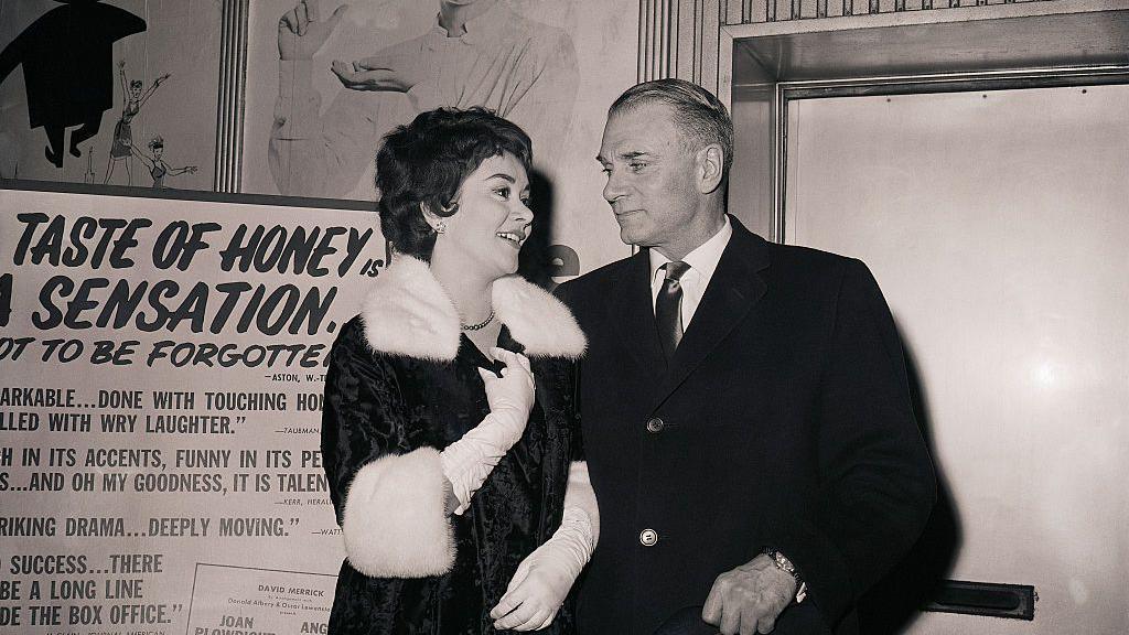 Joan Plowright and Sir Lawrence Olivier next to a poster for A Taste of Honey in 1961