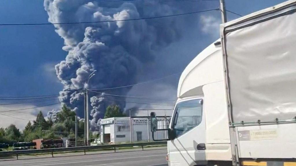 Smoke rises near a Wildberries warehouse in the distance. In the foreground is a lorry sitting in front of road