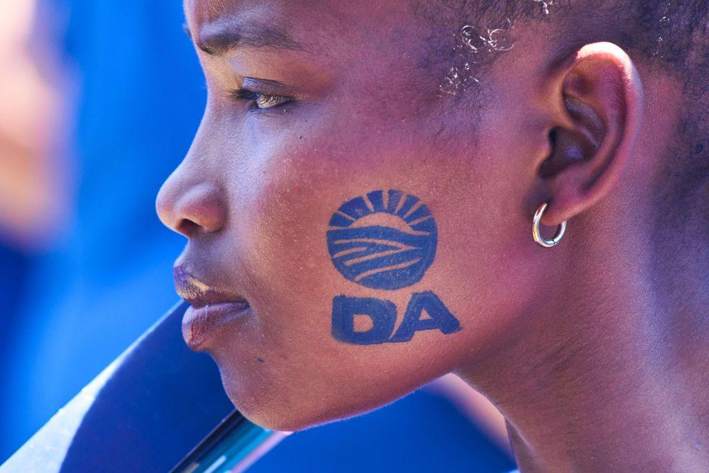 A black woman at a rally with the DA logo stamped on her face.