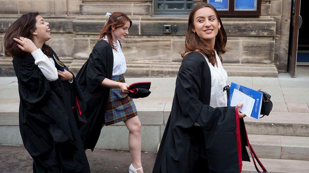 Three female graduands make their way through the streets of St Andrews and into a graduation ceremony at the University of St Andrews