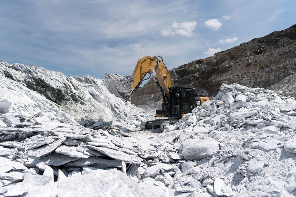 An excavator extracting ore from the talc vein in a quarry