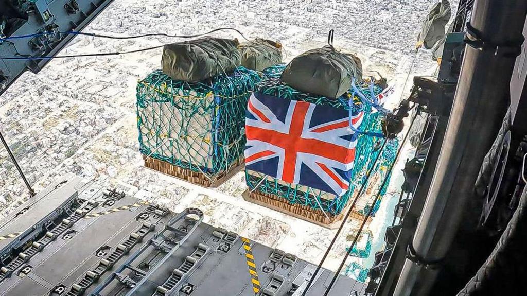 Humanitarian aid including water, rice, cooking oil, flour, tinned goods and baby formula wrapped in a Union Flag is airdropped over Gaza from a RAF A400M aircraft.