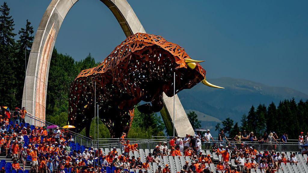 Fans sit in the grandstands underneath the bull statue at the Red Bull Ring 