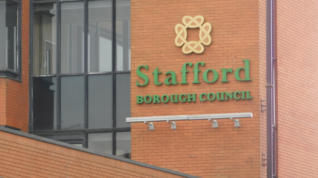 A red brick building, with black-framed windows to the left, and the words Stafford Borough Council in green to the right