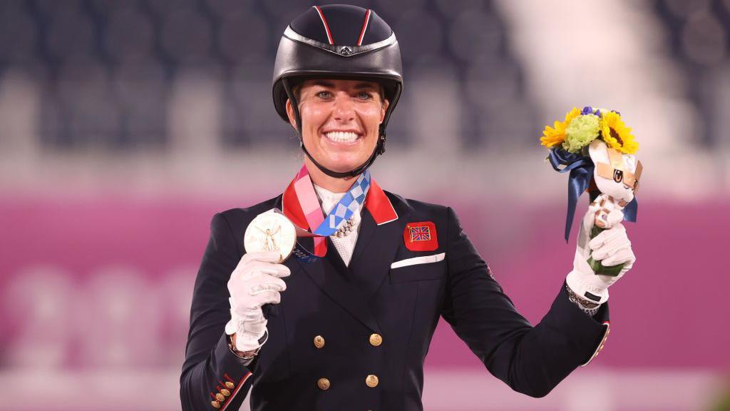 Charlotte Dujardin holding up her bronze medal from Tokyo 2021