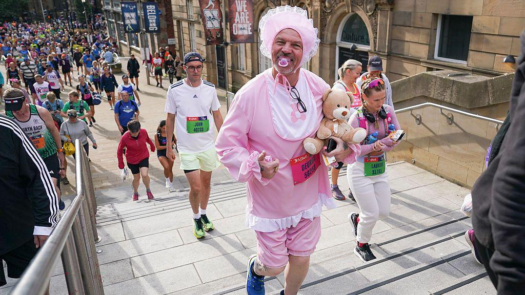 A man dressed up as a baby running.