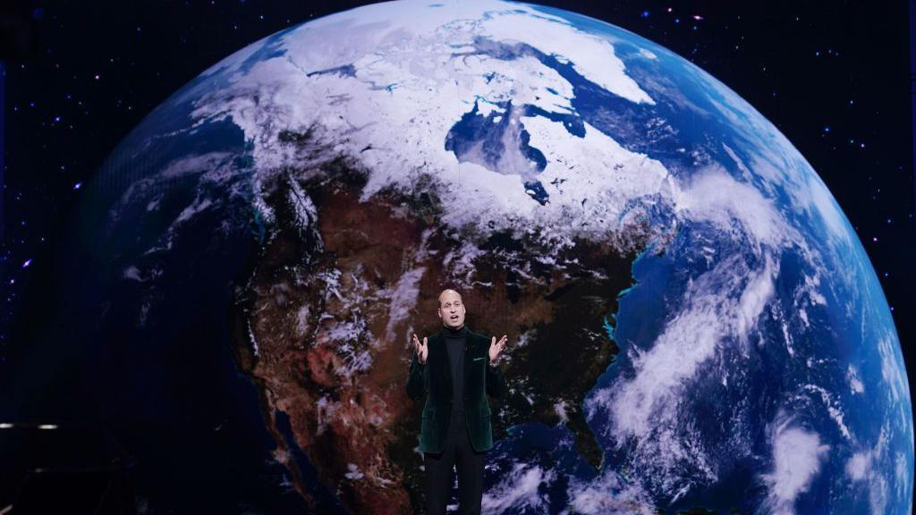 Prince William in front of an image of the Earth seen from space. 