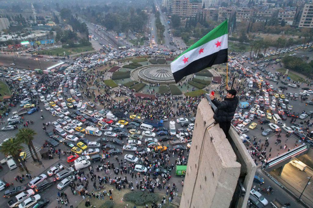 An aerial view shows a Syrian man waving a Syrian flag above Damascus' Umayyad Square