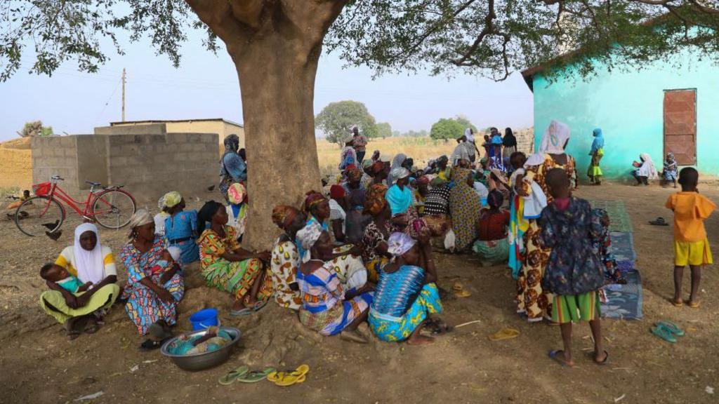 Women gather under a tree at a refugee settlement in Issakateng-Bausi, in Bawku, northern Ghana, on December 7, 2022