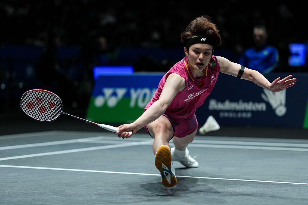 La jugadora de bádminton china Wang Zhiyi se estira para alcanzar un volante que cae y hace girar su raqueta hacia atrás en la cancha durante el Campeonato Abierto de Inglaterra en Birmingham.