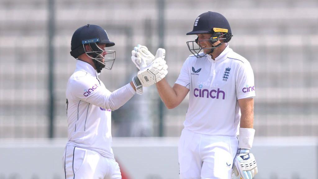 Joe Root is congratulated by Ben Duckett after breaking the record of Sir Alastair Cook for the most test runs for England during day three of the First Test Match between Pakistan and England