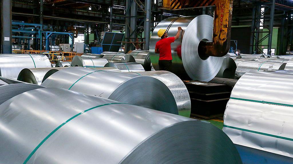 An employee writes on a coil of galvanized steel held by a coil grab crane at the manufacturing facility of Uttam Galva Steels Ltd., the Indian unit of ArcelorMittal, in Khopoli, Maharashtra, India.
