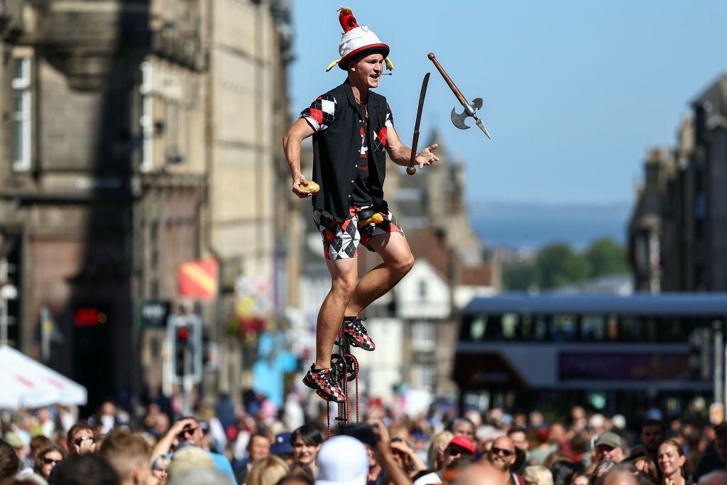 A juggling performer balancing on a unicycle at Edinburgh's Royal Mile during the city's Festival Fringe in 2024.