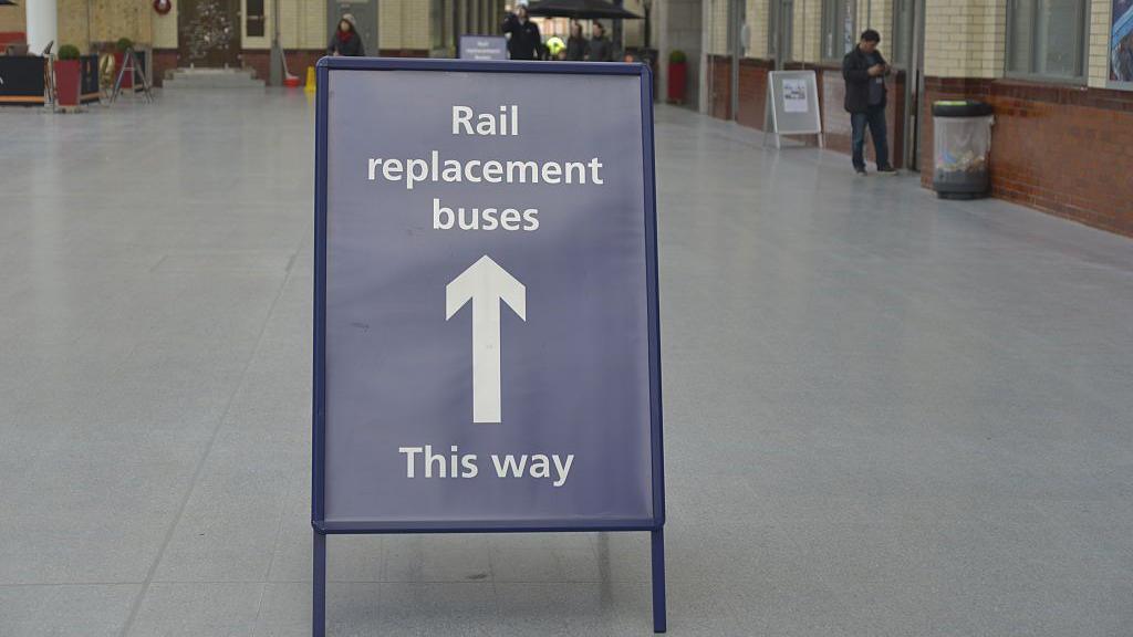 A sign at a railway station that reads "Rail replacement buses. This way."