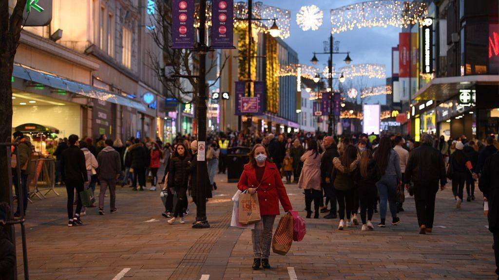 A street full of shoppers and Christmas lights twinkling.