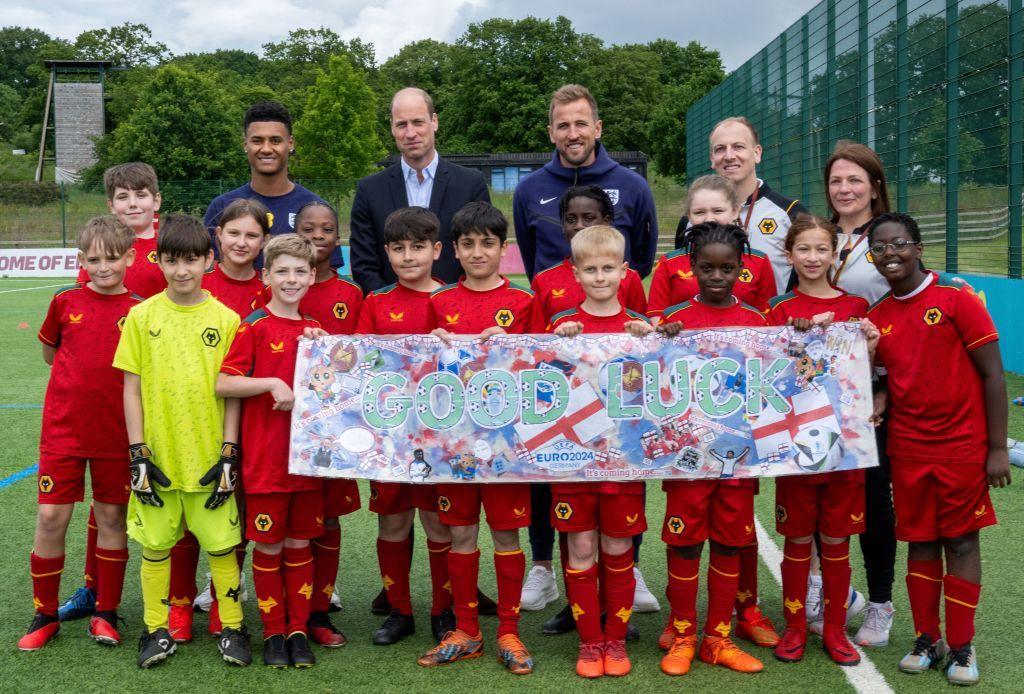 Prince William poses with children in football kits.