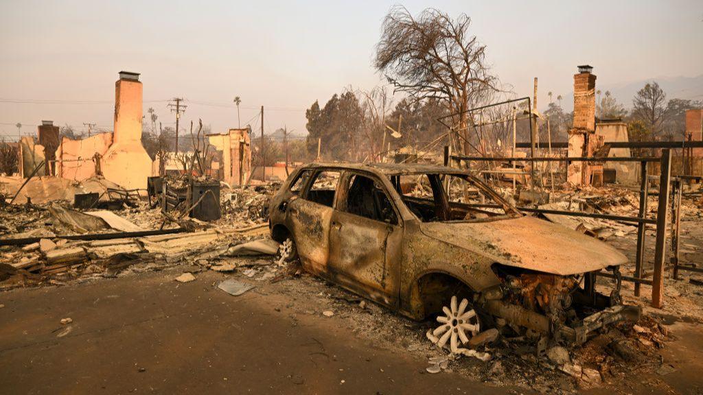 A burnt out car in the foreground of a totally destroyed landscape