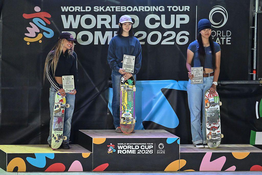 The three skaters are seen standing on the podium with their skateboards 