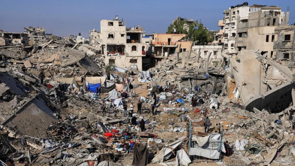 Residents of Gaza stand amongst rubble and ruins