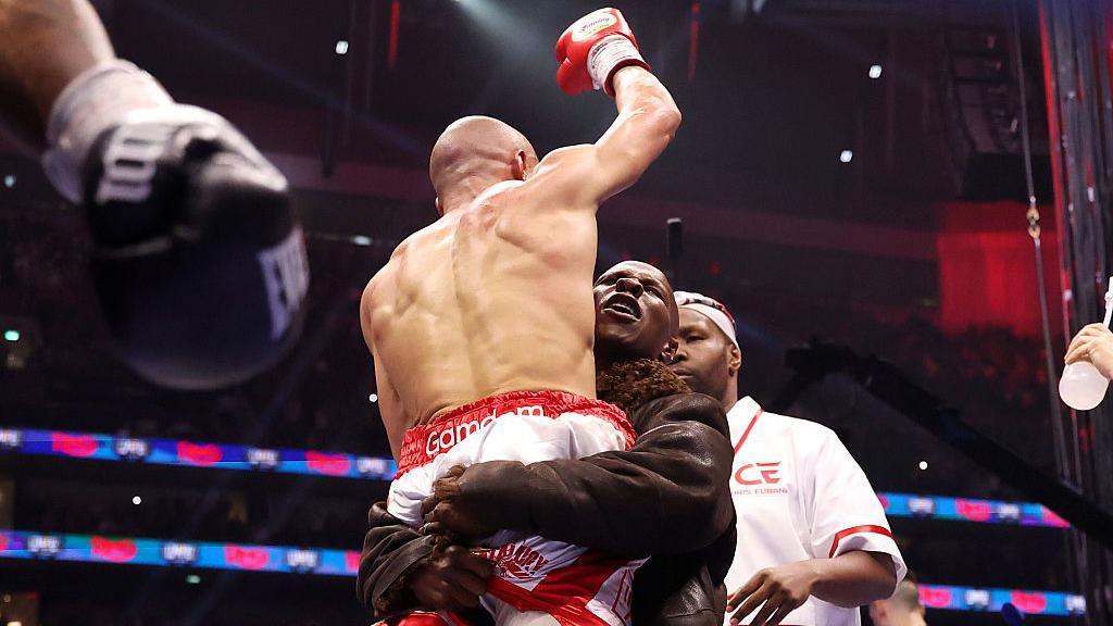 Chris Eubank Jr raises his arm into the air as he is lifted up by his father Chris Eubank Sr