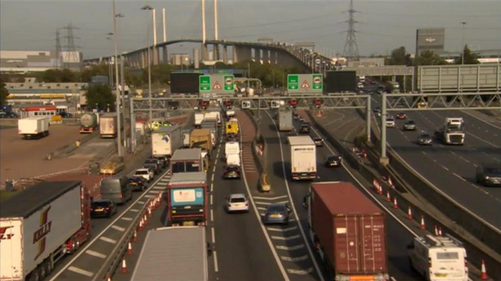 Vehicles making the crossing with the bridge in the distance