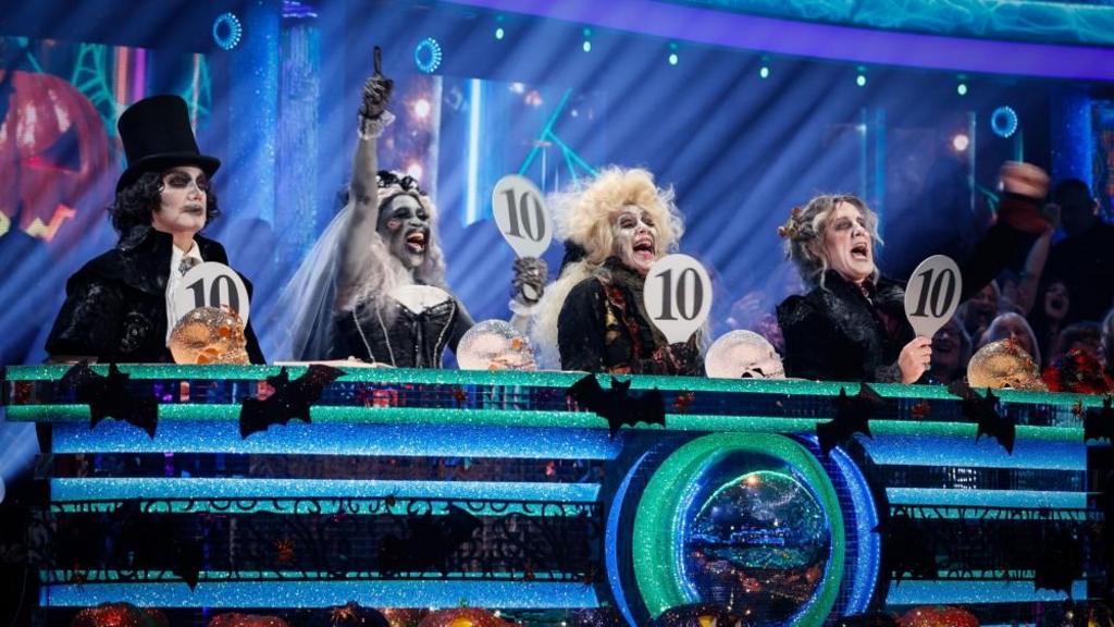 BC handout photo of Craig Revel Horwood, Motsi Mabuse, Shirley Ballas, and Anton Du Beke hold up their paddles and give four 10's to Lewis Cope.
