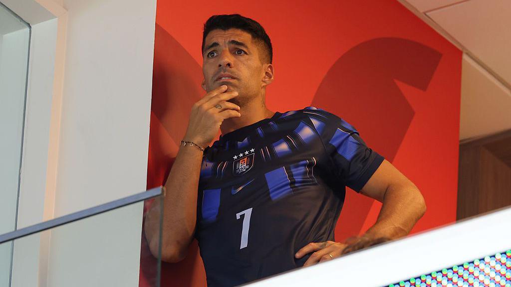 Close-up of Luis Suarez watching Uruguay at the World Cup, in a largely dark blue team shirt with the number 7 on the front