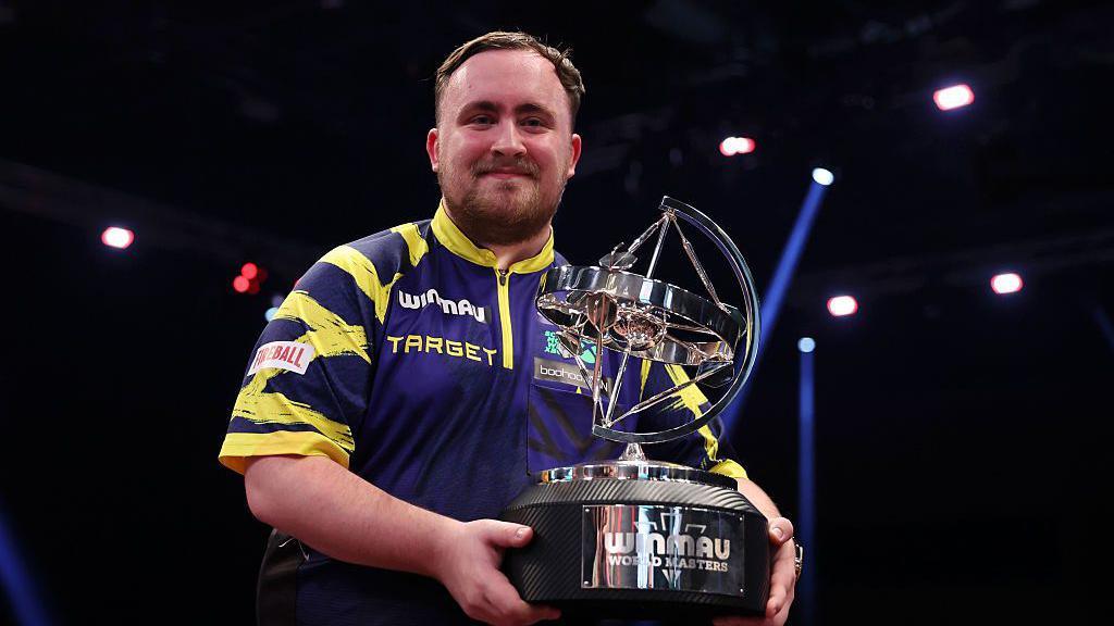 Luke Littler holding the men's World Matchplay trophy