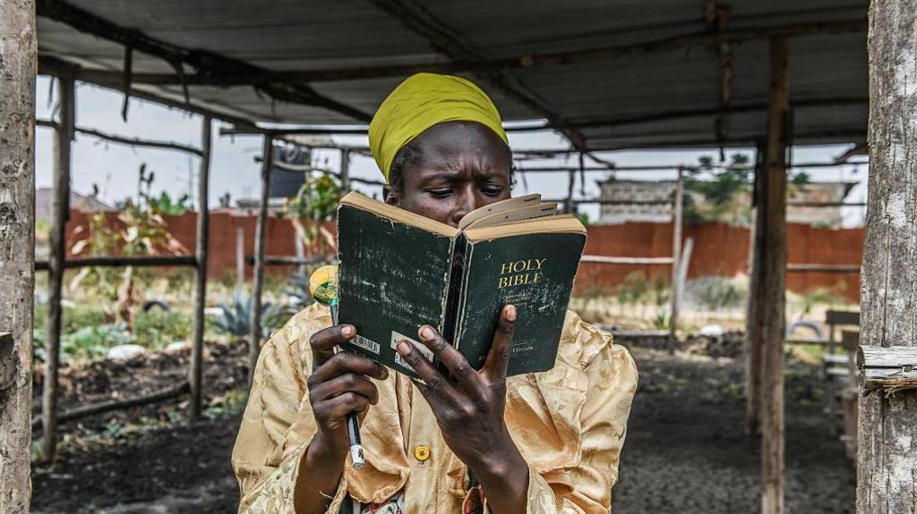 A man is reading a black bible under a roof in Nairobi, Kenya - Sunday 24 August 2025.