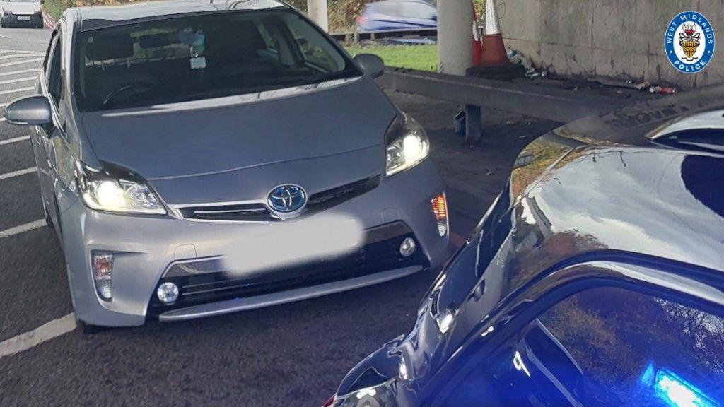 A silver car is on the left and middle of the photo. A darker vehicle is on the bottom right.