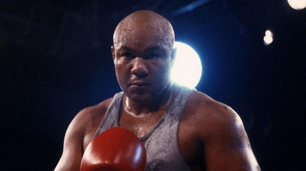 George Foreman pictured in 1989 with a shaved head with his face partially obscured in the darkness