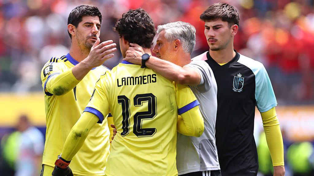 Senne Lammens getting a hug from Belgium's coach and Thibaut Courtois after a mistake with Mike Penders nearby