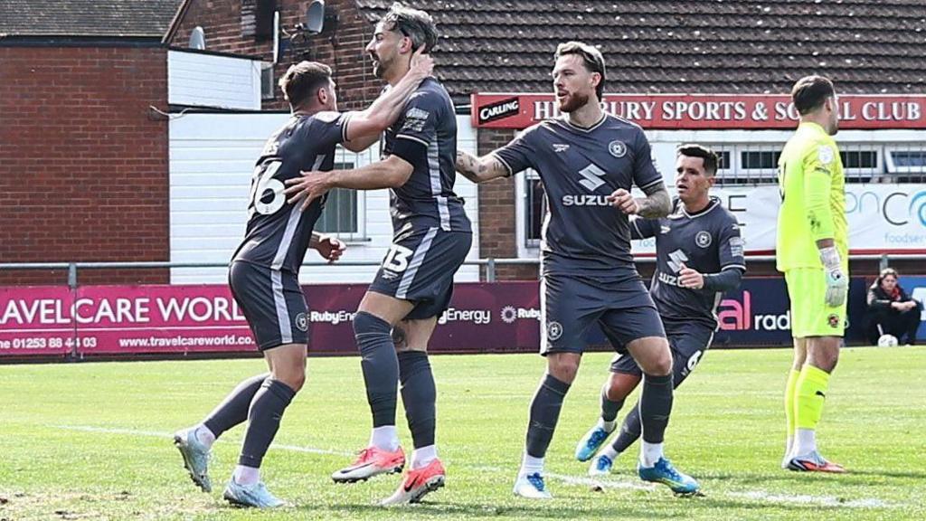MK Dons players congratulate team-mate Callum Paterson following his equalising goal at Fleetwood