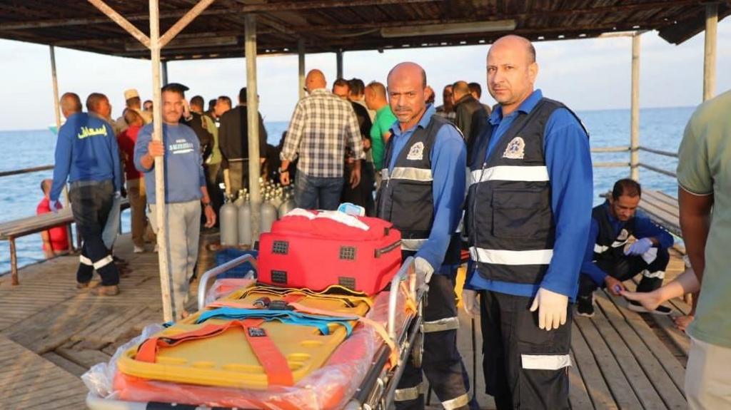 Medics wait for possible survivors after a boat sank at a harbour in Marsa Alam