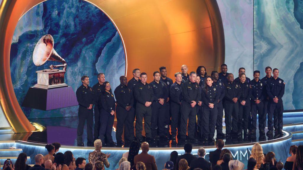 Los Angeles County firefighters crowd on stage at the Grammys in their uniforms 