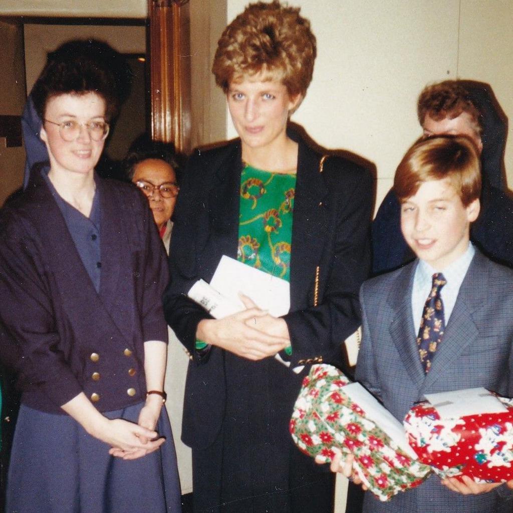 Diana, Princess of Wales, and Prince William at The Passage charity. The prince is carrying two Christmas presents. A nun stands to the left of the princess.