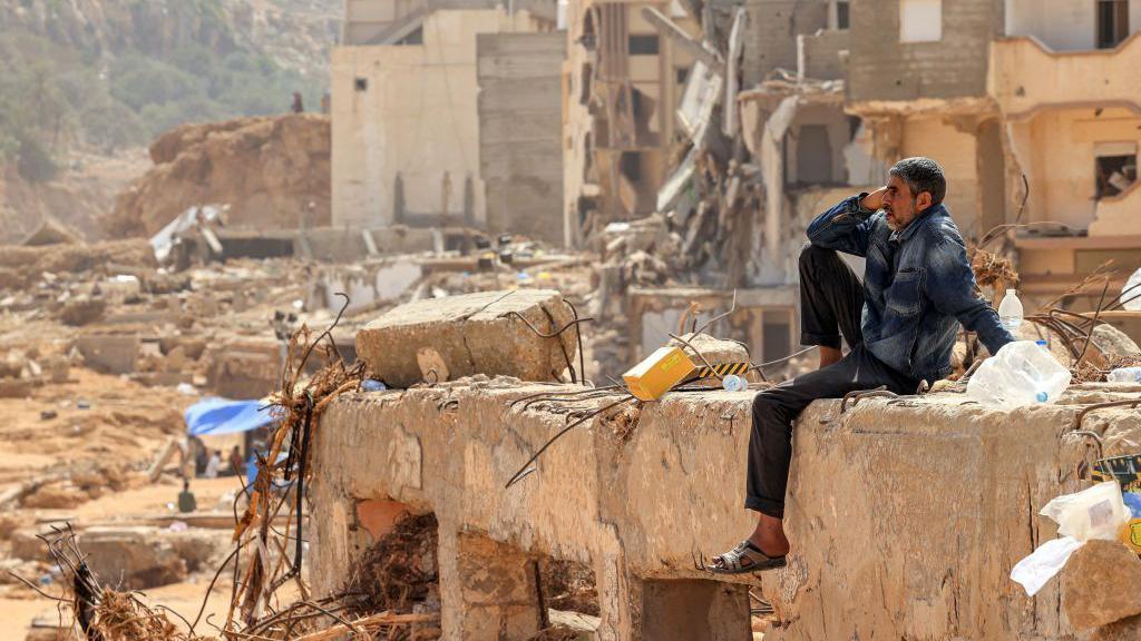 A man reacts as he sits on the rubble of a destroyed building in Libya's eastern city of Derna on 18 September 2023 following deadly flash floods