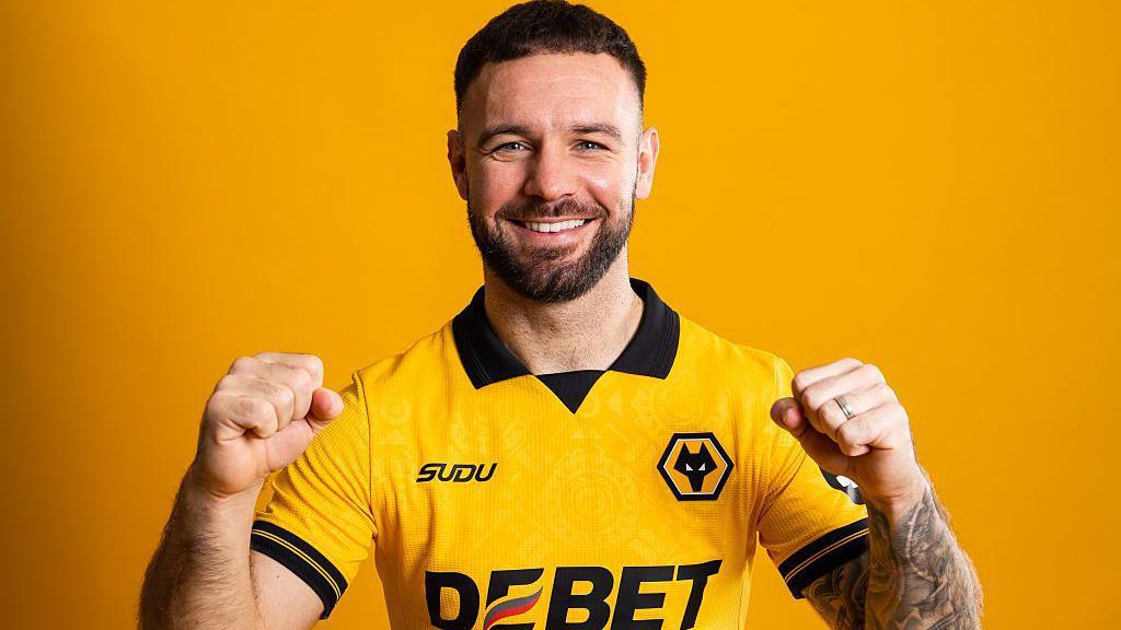 Adam Armstrong, wearing a Wolves shirt, raises both fists 