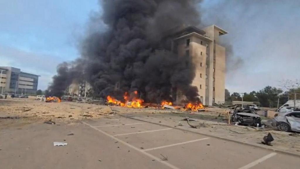 A building burns with black smoke seen rising above fire from the foot of the building, obscuring most of the facade.