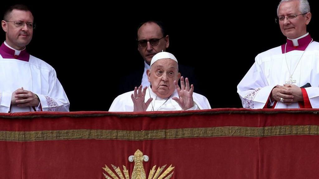 Pope Francis waves to the crowds from the balcony overlooking St Peter's Square on Sunday accompanied by a number of members of the clergy.